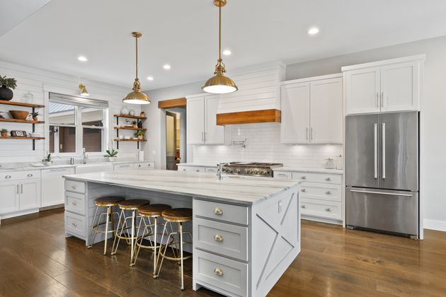 Modern farmhouse kitchen with a gray island, white cabinets, and warm wooden details.